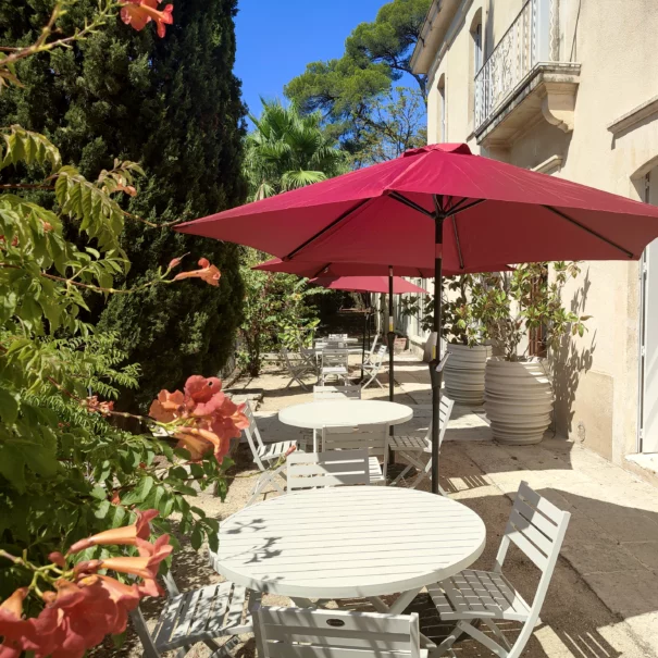 La terrasse de la Bastide Castella, demeure de charme à Montpellier, équipée de tables, chaises et parasols.