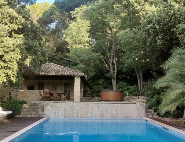 La piscine de la Bastide Castella. On voit le Pool House derrière elle ainsi qu'un jacuzzi.