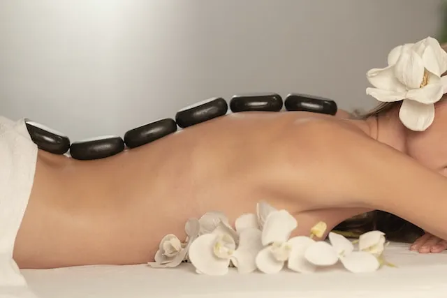 Une femme allongée avec des pierres sur le dos et des fleurs dans les cheveux.