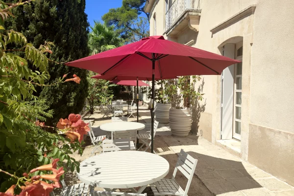 La terrasse de la Bastide Castella, demeure de charme à Montpellier, équipée de tables, chaises et parasols.